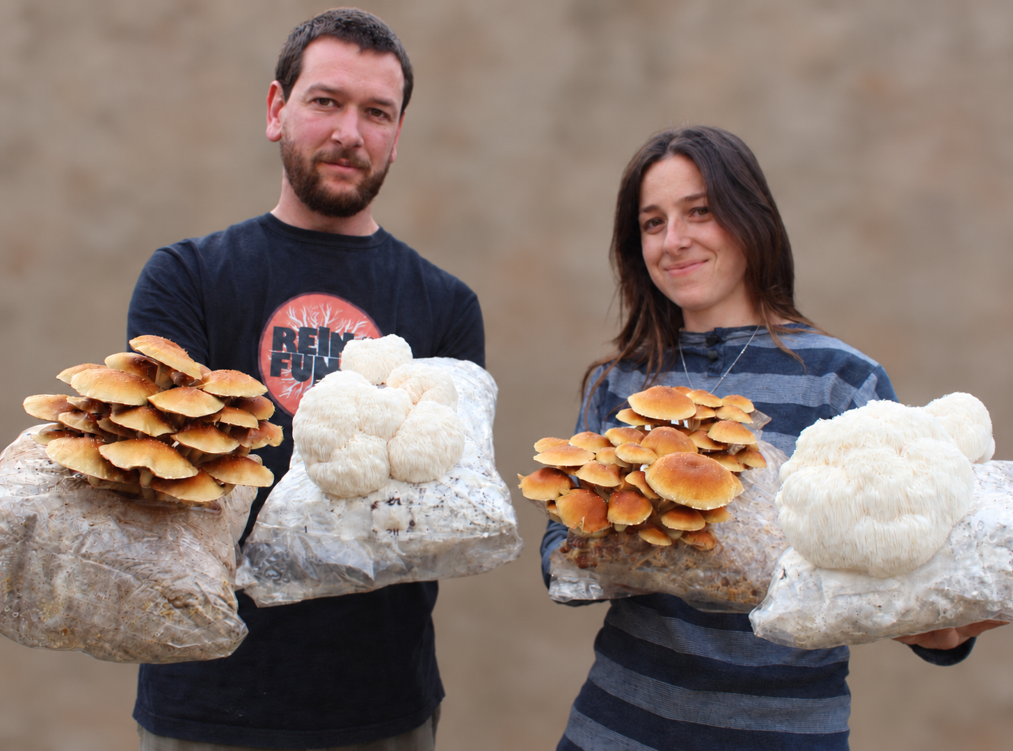 Dos integrantes de Reino Fungi mostrando bloques de cultivo con hongos